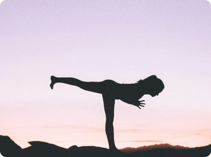 mujer practicando yoga al aire libre al atardecer realizando la pose del guerrero 3