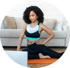 mujer practicando yoga online sentada en el piso de su casa realizando la pose de la paloma