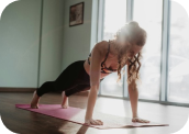 mujer practicando yoga en el piso de un studio realizando la postura de la plancha alta